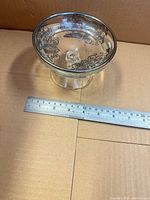 Oblique view showing pedestal form, silver rim, black decoration, ruler for scale