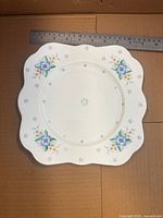 Front view of Colclough plate showing pattern, scalloped square shape, ruler for size reference