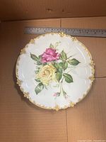 Front view showing floral design, scalloped gold rim and ruler for scale