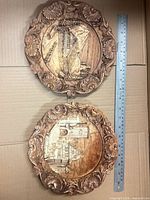Front view of both carved wooden plaques with ruler for scale