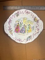 Front view of handled cake plate showing pattern and ribbon border