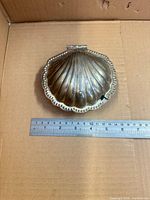 closed clam shell serving dish next to ruler