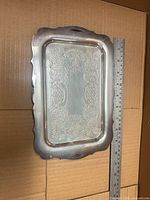 front of silver-plated tray showing floral engraving and ruler for scale