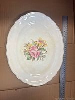 Top view of oval platter showing floral design, scalloped rim, ruler for scale