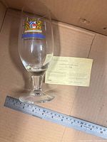 Goblet in box with crest visible, metric ruler for scale