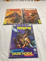 Front view of three bagged Dark Horse comics: two Predator: Primal issues and one sealed Alien vs. Predator pack