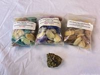 Three sealed bags of felted wool melts labeled Woodsy, Melt-Down, Cedar and one pyrite specimen