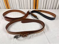 Three leather belts arranged showing colors and buckles