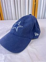 Front three-quarter view of navy cap showing Dallas Cowboys star logo and New Era flag embroidery