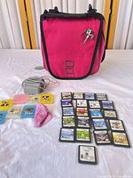 Full lot showing pink carrying case, charger, coloured game cases, cloth and array of cartridges