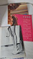 Stack of pin-up pages showing 1990 calendar sheet and Marilyn Monroe photo page