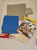 Overview of grey, blue baseplates, manuals stack, red speeder, white boat hull