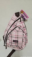 Front view of pink plaid Trailmaker sling backpack with tag attached