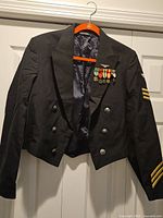 Full view of front of jacket on hanger showing buttons, ribbons and sleeve stripes