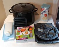 Group shot showing stock pot, nonstick plates, Pop Chef kit, cracker tin, plastic bottle