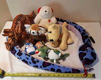 Group shot of all eight plush toys on table, tape for scale