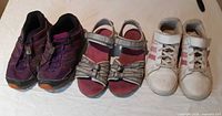 Front view of three footwear pairs: Salomon sneakers, Teva sandals, Adidas sneakers
