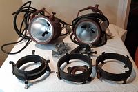Two Fresnel lights, cables, clamps and baffles displayed on table
