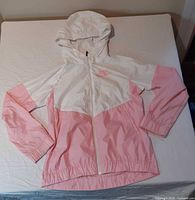 Front view of pink and white Nike hooded windbreaker