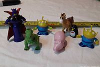 Group shot of all seven Toy Story figures with tape measure for scale