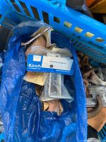 Kirsch curtain rod supports in package within blue bag alongside rusted hooks and other loose hardware
