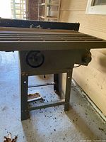 Full view of table saw on stand showing cast iron top, adjustment wheel, motor housing and overall wear