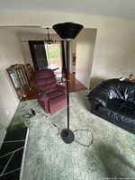 full view of black metal torchiere floor lamp standing in room