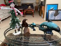 Group view of wooden eagle, three ceramic dolphins, and snowman decoration on glass table