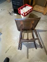 Table on its side showing turned spindle legs and lower shelf
