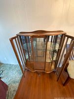 Front view of curved glass curio cabinet showing door and shelves
