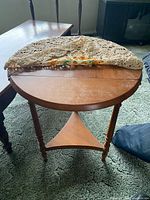 End table with one leaf raised showing round top, crocheted doily partially on surface, turned legs, lower shelf