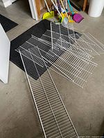 Assorted white wire shelves laid out on floor showing varying lengths and depth