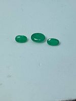 Three oval emeralds side by side on light background
