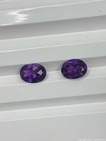 Pair of oval amethyst gemstones on white background
