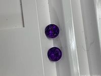 Pair of round amethyst gemstones on white background showing color and cut