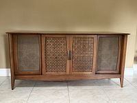 front view of stereo console showing three woven cane panels and wood frame