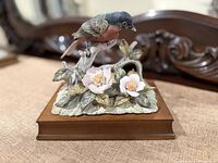 Front view of porcelain bird figurine on wood base showing bird, flowers, leaves