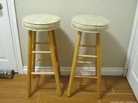 Two matching fabric-topped wooden bar stools