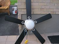 Front view of five-blade ceiling fan showing silver housing, white center, black blades, and wiring