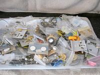 Tray spread showing numerous earrings on cards and in bags