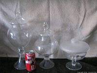 three glass candy bowls with lids beside soda can for scale