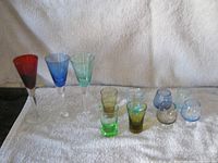All 11 coloured liqueur and shot glasses arranged on a towel