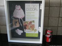 Front view of packaged Studio Décor shadow box next to soda can for scale