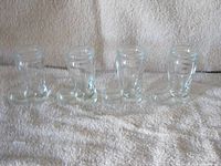 Front view of four clear glass boot-shaped shot glasses in a row