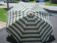 Top view of open umbrella showing green and off-white striped canopy