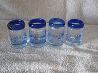 Front view of four Tequila Corazón shot glasses with blue rims and branding