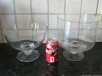 Both clear glass trifle bowls beside soda can for scale