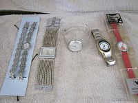 All five wristwatches displayed on towel; two sealed Disney watches on right, three loose watches on left