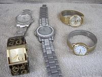 Group shot of five assorted wristwatches laid on towel