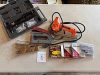 Overview showing rivet gun kit in case, two manual staplers, electric stapler, and boxes of staples